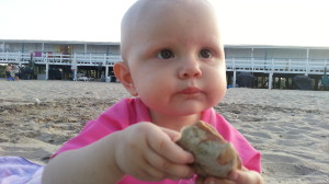 Nicole put Sally on a blanket and let her put her feet in the sand, about as risky as we'd get. Here, she's showing you one of William's shells he found. 